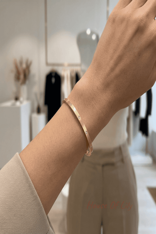 Stylish woman in a modern boutique wearing a slim gold bangle on her wrist, showcasing minimalist jewelry in a chic setting.