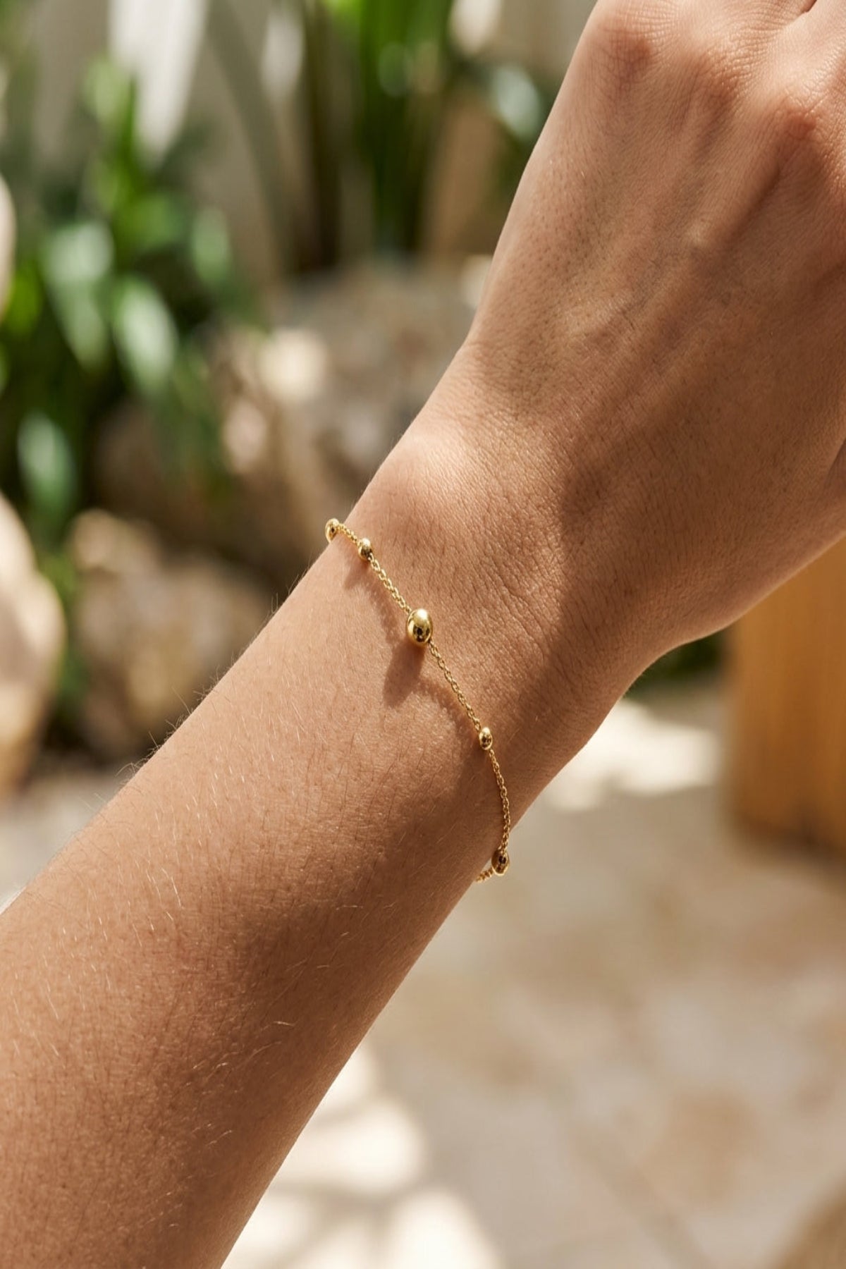Full-body shot of a woman wearing the minimalist stainless steel bracelet in a natural, softly lit environment.